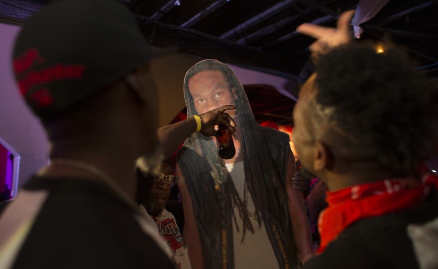 At the 2nd Annual Fallen Bikers Memorial Party in New Orleans on Nov. 12, 2016, fellow Insane Hunters bike club members celebrate with a cutout poster of Michael "Insane Flash" Troy Stradford-Francis.