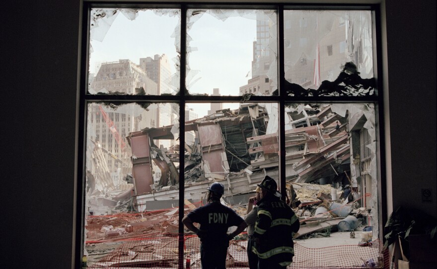 Firefighters survey the wreckage of the World Trade Center through blown-out windows of a World Financial Center building.