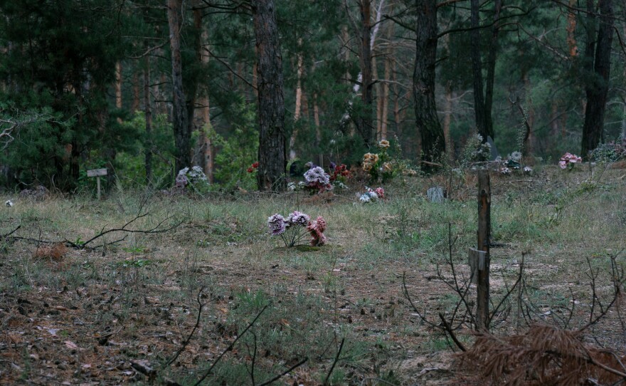 Many of the individual graves at the mass grave site are decorated with plastic flowers, or draped in cloth.