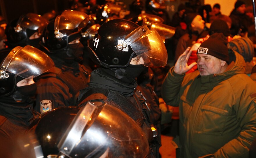 Ukrainian police block the road as supporters of former Georgian President Mikhail Saakashvili gather in Kiev outside the police station where he was taken after his arrest late Friday.