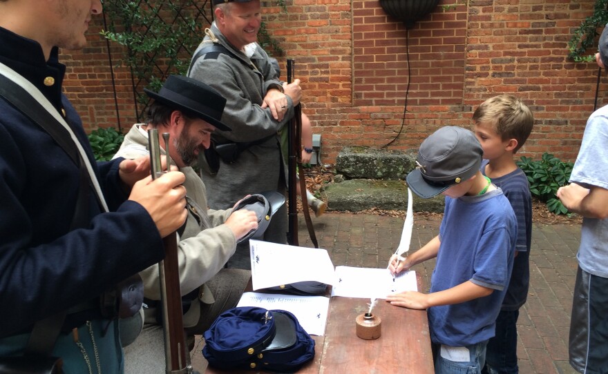 As Will Ruark, Jason Luker and Jay England look on, kids sign up to fight in a mock battle for the Confederacy or Union.