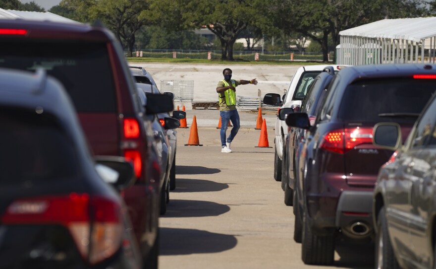 An election worker guides voters in cars at a drive-through voting site in Houston on Oct. 7.