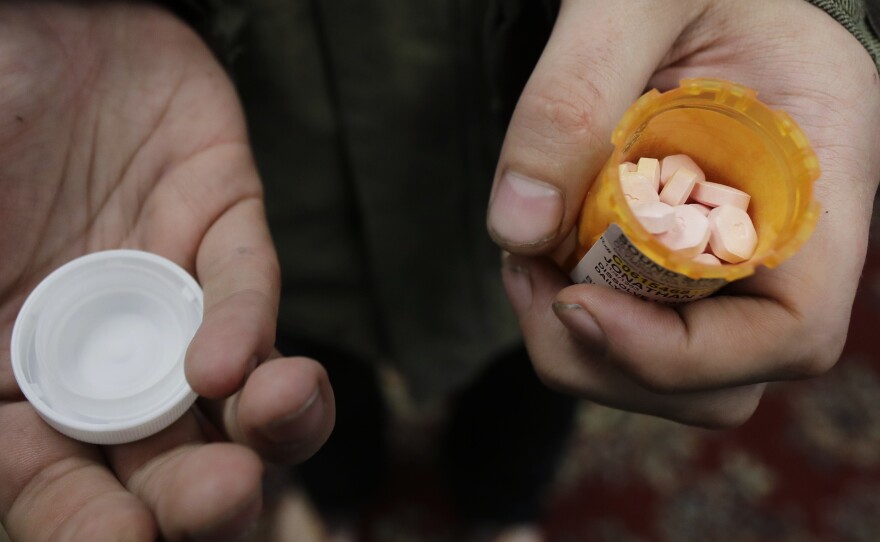 A person with addiction holds a bottle of buprenorphine, a medicine that prevents withdrawal sickness in people trying to stop using opiates, as he prepares to take a dose in a clinic in Olympia, Wash (AP Photo/Ted S. Warren)