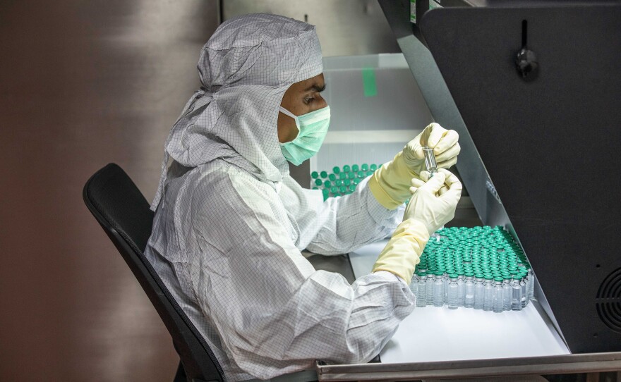 A technician checks for any deficiencies in vaccine doses and vials.