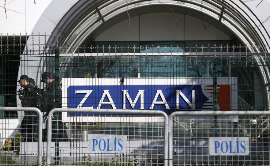 Riot police officers walk past the headquarters of Zaman newspaper, surrounded by police barriers in Istanbul, on March 6. Police used tear gas and water cannons to disperse hundreds of protesters who gathered in support of the paper outside its headquarters.
