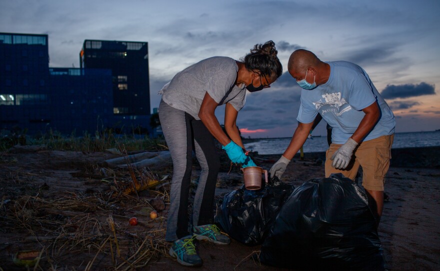 Syeada Manbodh and Bryan D'andrade, with the group Seawalls and Beyond, collect trash left on the beach. Other citizen-led environmental initiatives in Guyana are working to rebuild native mangrove forests, which act as natural sea defenses and prevent erosion.