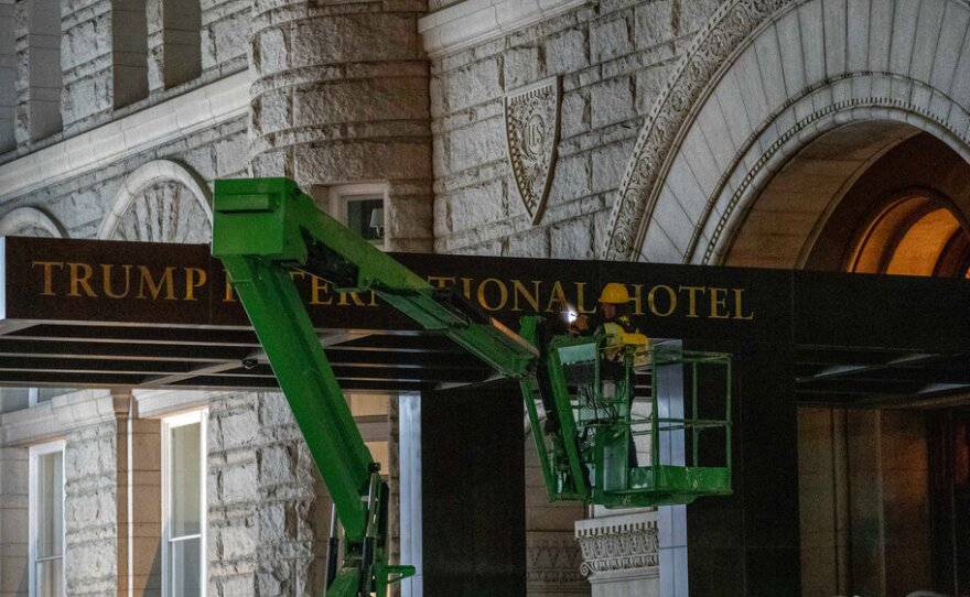 A worker removes the signage for the Trump International Hotel on Wednesday, in Washington.