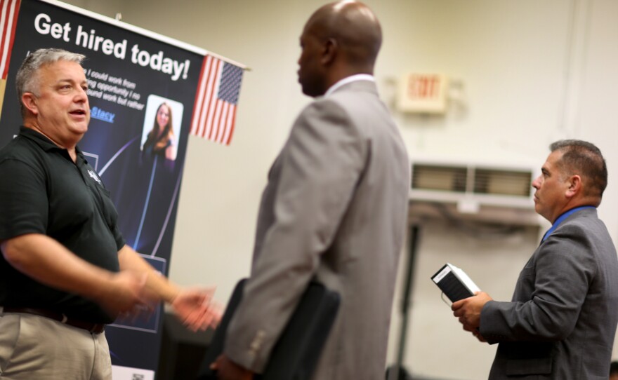 Hans Kahl (left) speaks with prospective employees a job fair for veterans in Miami on Tuesday. With job growth still slow, the Federal Reserve may keep trying to stimulate the economy.