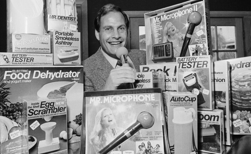 In this 1982 file photo, Ron Popeil, the man behind those late-night, rapid-fire television commercials that sell everything from the Mr. Microphone to the Pocket Fisherman to the classic Veg-a-Matic, sits surrounded by his wares in his office in Beverly Hills, Calif. Popeil died Wednesday, July 28, 2021 his family said.