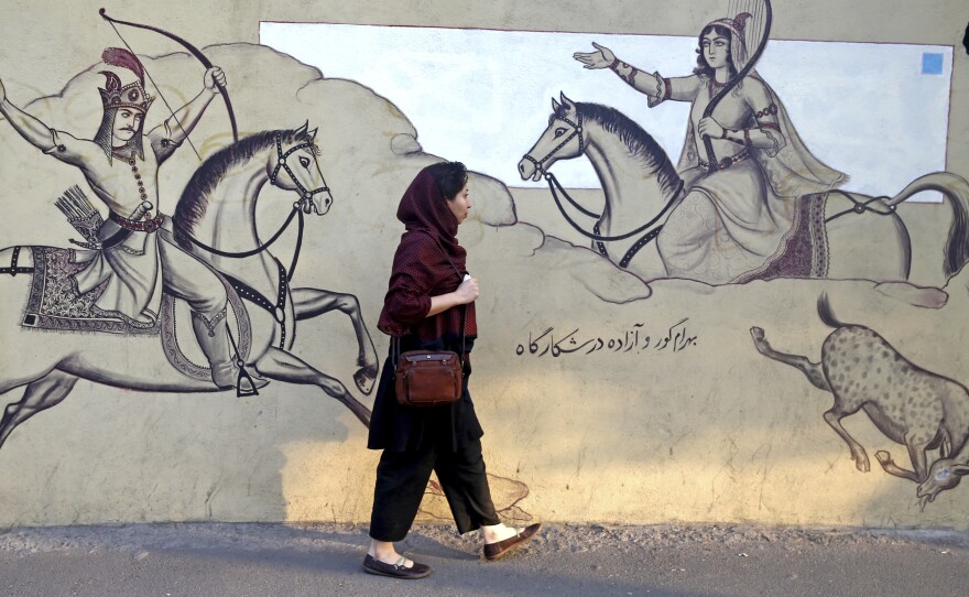 An Iranian woman walks past a wall mural last month in downtown Tehran, Iran.