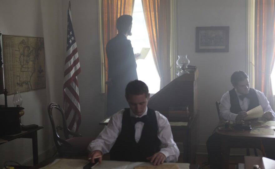 Lincoln reading a telegraph at the window of the telegraph office.