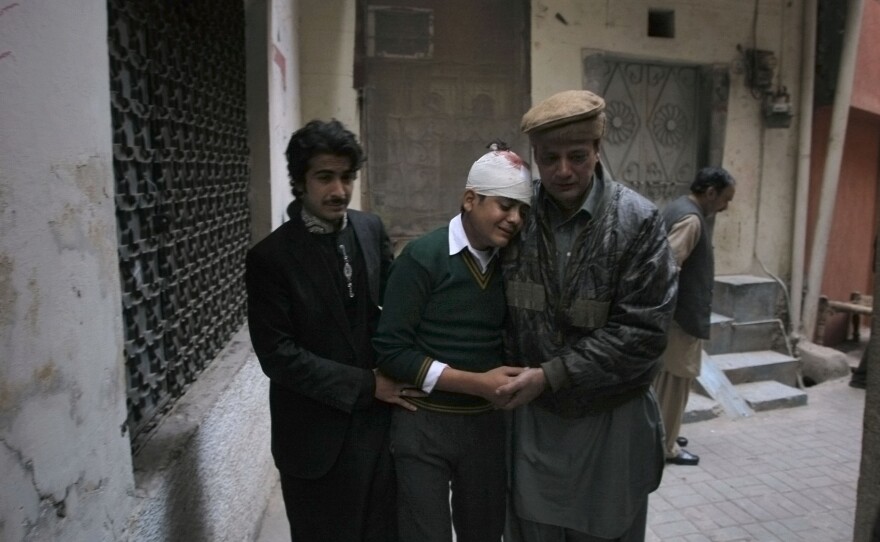 The uncle and cousin of injured student Mohammad Baqair, center, comfort him as he mourns the death of his mother who was a teacher at the school which was attacked by Taliban, in Peshawar, Pakistan, on Tuesday.