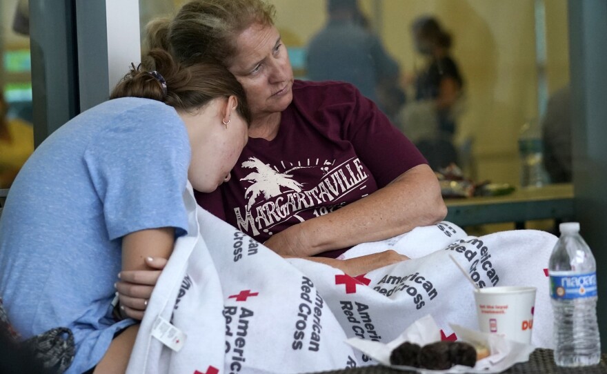 Jennifer Carr, right, sits with her daughter as they wait for news at a family reunification center near the partially collapsed building. Carr and her family were evacuated from a nearby building.