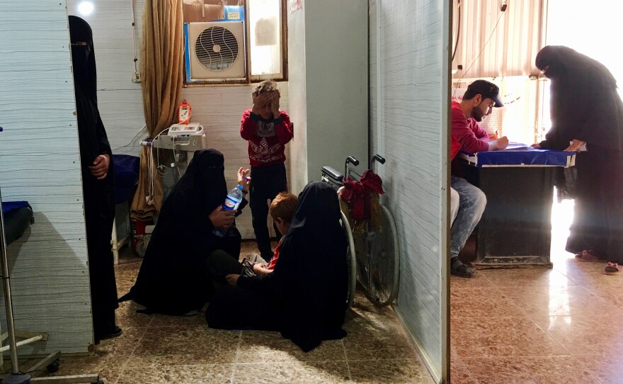 Women sit on the floor as they wait in a clinic at the al-Hol detention camp.