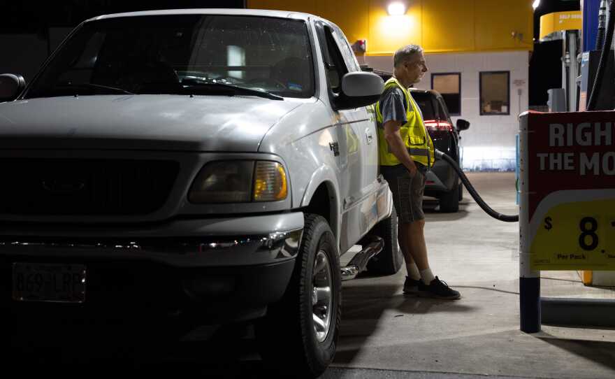 A person waits while filling their fuel tank at a gas station in Portland, Ore.