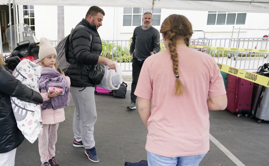 Phil Metzger, center in back, of the Christian church Calvary San Diego, talks with volunteers as they help Ukrainians arriving after crossing into the United States from Tijuana, Mexico, Friday, April 1, 2022, in Chula Vista, Calif.
