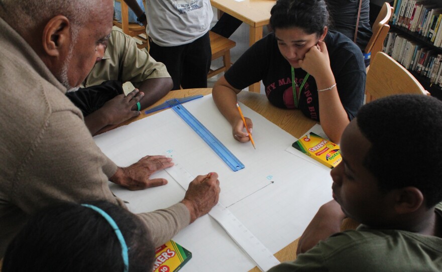 Moses shows students how to measure slopes using a ruler made by the students. His Algebra Project classroom model uses a lot of hands-on tools to help kids make math less abstract.