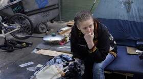 A homeless woman sits with a bag containing her belongings in San Francisco, March 1, 2016.