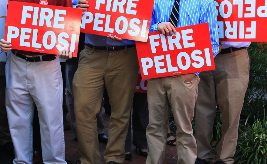 Capitol Hill staffers hold signs while participating in the launching of the RNC-sponsored "Fire Pelosi" bus tour last September in Washington. The former House speaker says she doesn't have time to worry about the attacks on her. "You just have to decide," she says. "Do I care about that, or do I care about getting a job done?"
