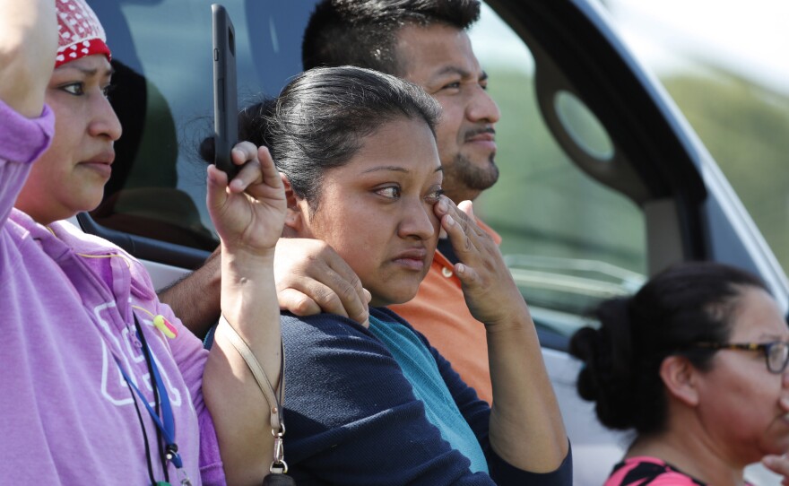 Friends, co-workers and family watch as U.S. immigration officials raid the Koch Foods Inc. plant in Morton, Miss., on Wednesday.