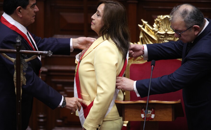 President of Congress José Williams (left) and Sen. Jose Cevasco place the presidential sash on Vice President Dina Boluarte as she is sworn in as the country's new president in Lima on Dec. 7.