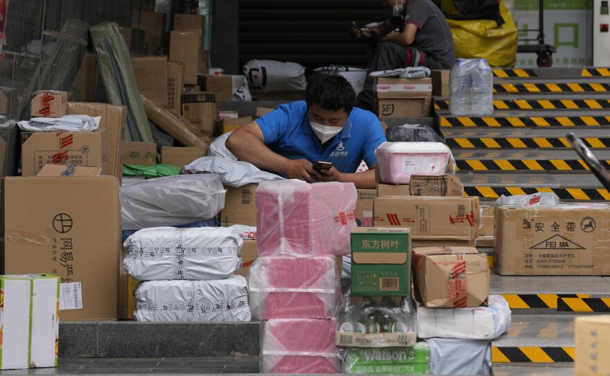 Delivery men sort out their parcels outside a community on Tuesday, May 31, 2022, in Beijing.