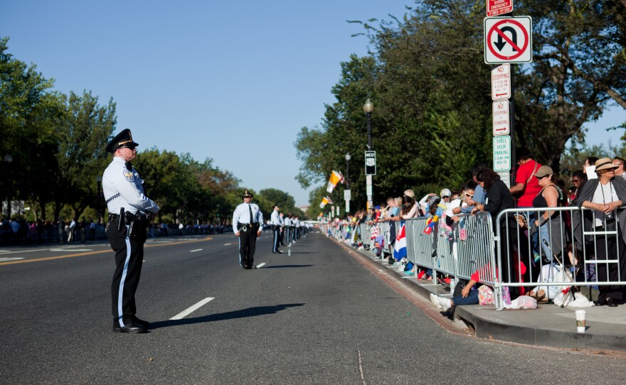 Security keeps spectators off the parade route on Constitution Avenue before the papal parade begins.