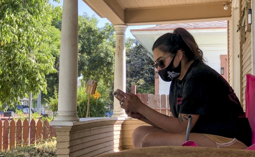 Gabriella Aldana, 24, rests on the front porch of the house she rents in Riverside on Aug. 7, 2020. Aldana has been moving houses since she and her two children were evicted from an apartment on March 26 and expects to be evicted from her current house if the federal unemployment boost isn’t approved and distributed before Sept. 1. 