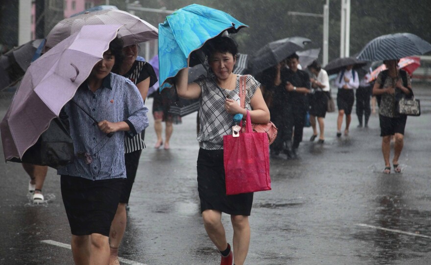 Pedestrians shield themselves from wind and rain brought by Typhoon Lingling Saturday, in Pyongyang, North Korea.