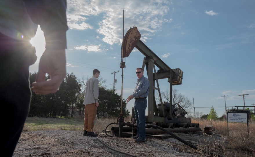 Carter Arthur (left) and Dan Arthur examine an active pumpjack in Sperry, Okla., on March 20, 2024.