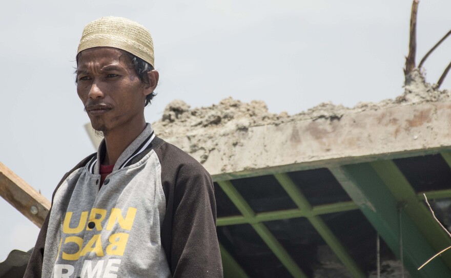 Muhlis Ipul, 32, stands before the remains of his modest home in Petobo, where the earthquake swept away his wife and two daughters. Ipul says his most painful memory is his youngest daughter, Windy, slipping from his grasp as they ran from their house, and he tumbled head over heels as the asphalt buckled beneath him.