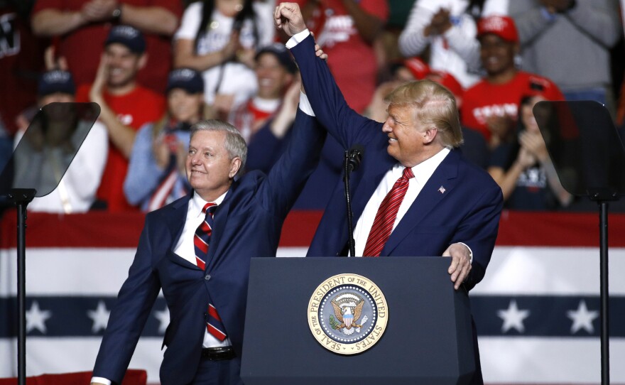 Sen. Lindsey Graham, R-S.C., stands onstage with President Donald Trump during a Feb. 28 campaign rally, in North Charleston, S.C. His allegiance to Trump has left some moderate voters feeling snubbed and switching allegiances ahead to Democrat Jaime Harrison.