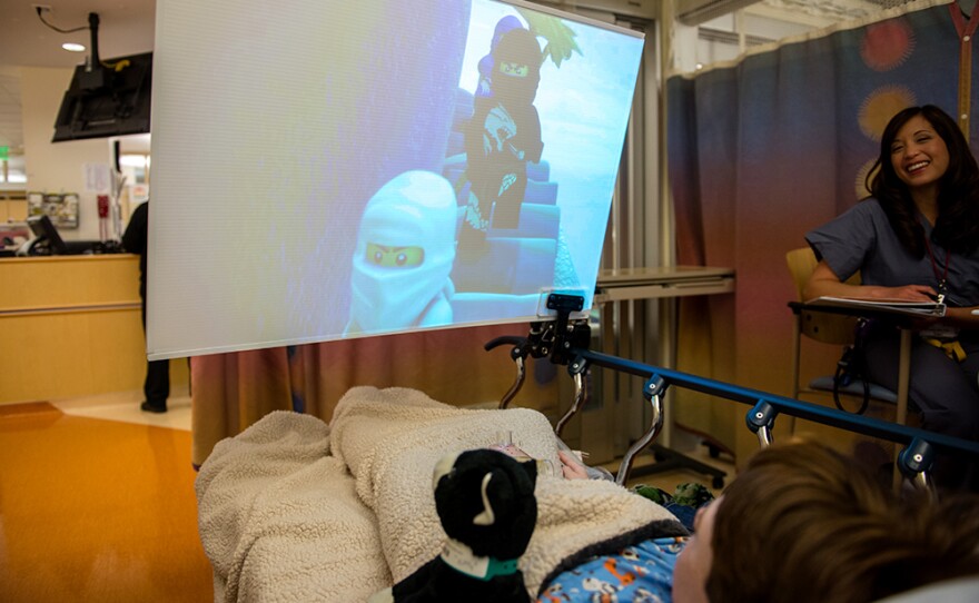 Kids waiting for surgery at the hospital can choose from a menu of age-appropriate entertainment options that include certain TV shows, movies and music videos. The big, close screen helps make the experience "immersive," the doctors who designed it say.