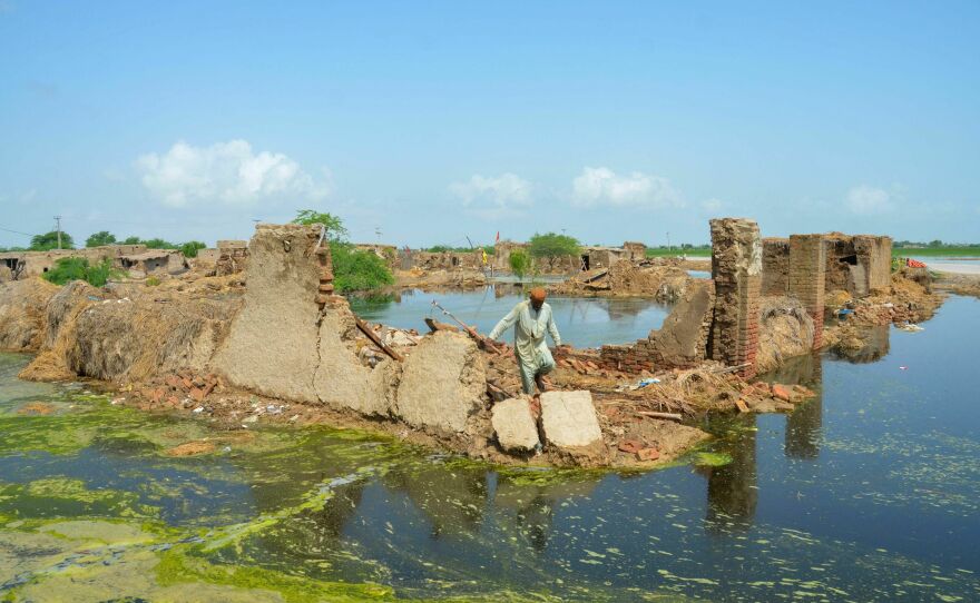 A man walks over his collapsed mud house after heavy monsoon rains in Pakistan in 2022. Climate change makes heavy rain more common, because a hotter atmosphere can hold more moisture.