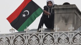 An anti-Gaddafi protestor sits on the roof of the Libyan Embassy on March 17, 2011 in London, England. Police are surrounding the embassy after protestors climbed onto the roof yesterday. 