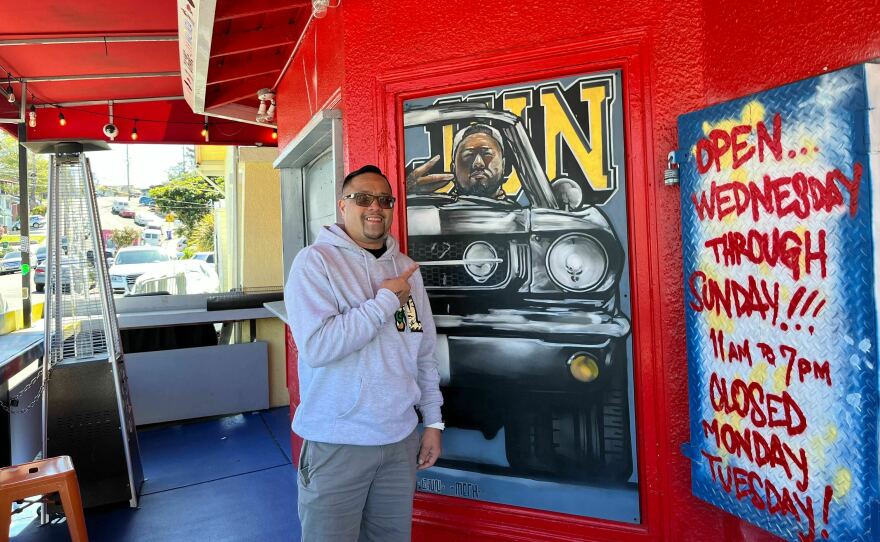 Mark Legaspi points to a painting of his cousin Jun Anabo at the successful Filipino restaurant they founded together. "I mean it's almost a year I would like to know something," he says of his cousin's unsolved murder.