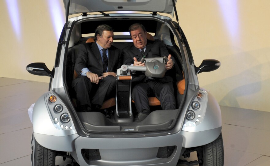 The then-president of the European Commission, Jose Manuel Barroso (left), and Jesus Echave, the Spanish chairman of a consortium of seven small Basque companies, sit together in a prototype of the Hiriko car, during a 2012 event in Brussels.