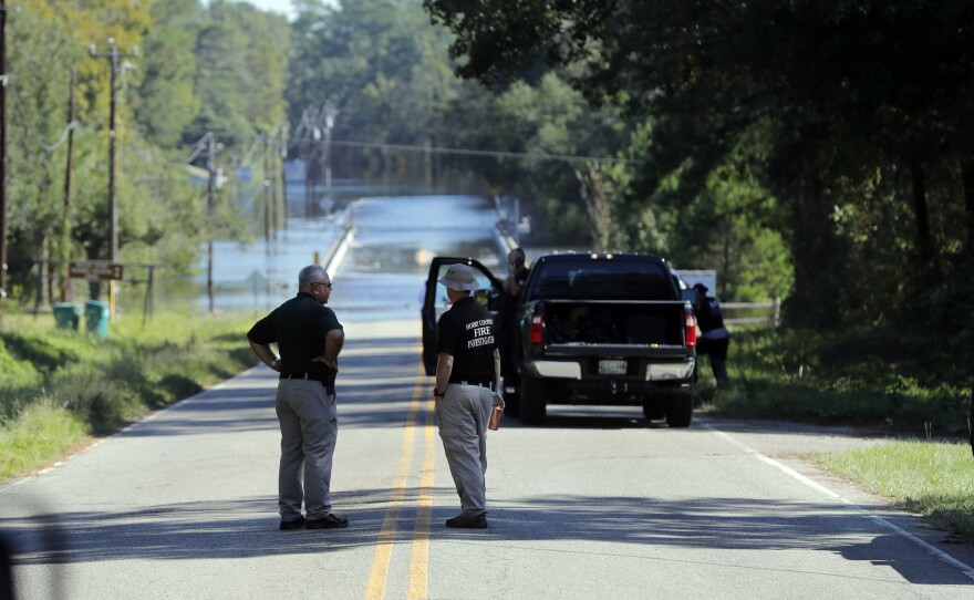 Officers stand near where two people drowned in a Horry County Sheriff's transport van overturned by floodwaters in South Carolina.