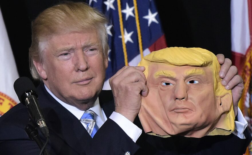 Donald Trump holds up a mask of himself during a rally in Florida in November 2016.