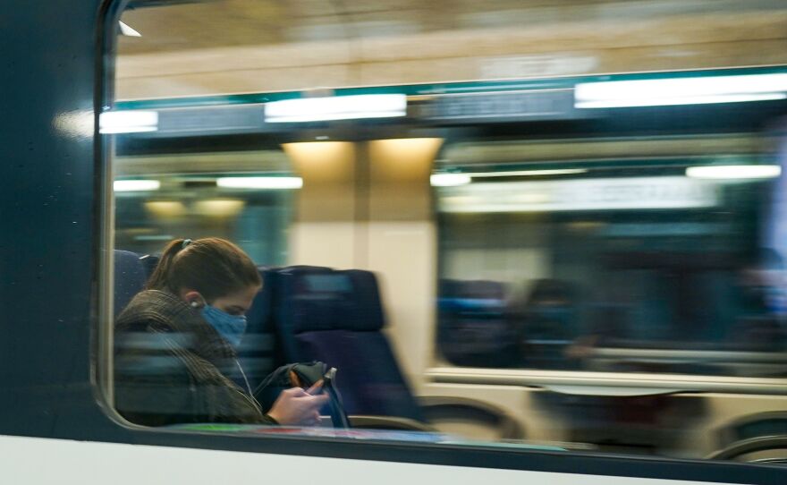 A commuter wearing a protective face mask looks at her mobile phone in a train arriving at the Central Train Station in Brussels in May 2020. Belgium's new rule addresses the ever-blurry line between work and personal life in the pandemic.