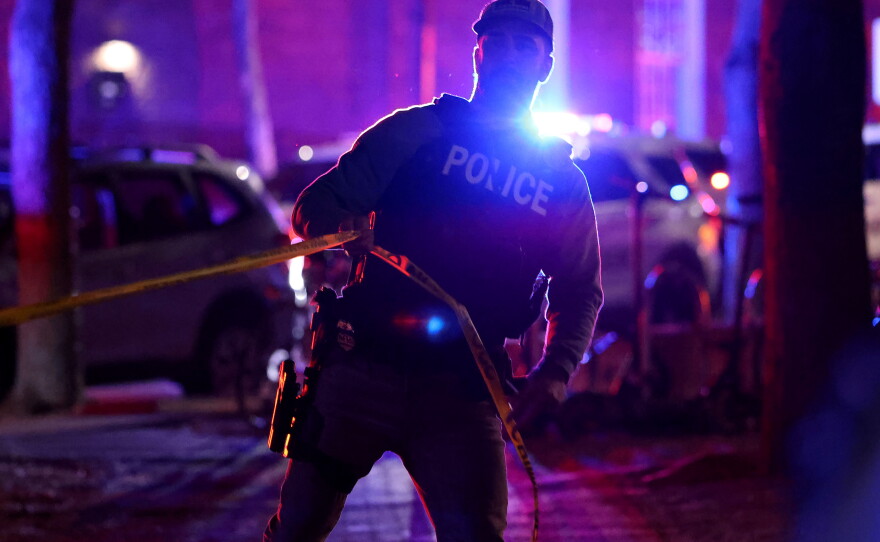 A police officer hangs yellow crime tape at Brown University in Providence, R.I., on Dec. 13, 2025, during the investigation of a shooting.