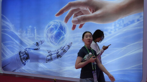 Visitors walk past a display depicting artificial intelligence and a human hand at the China International Supply Chain Expo in Beijing on June 22.