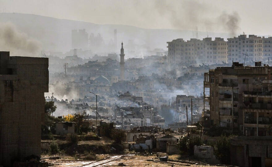In this photo released by the Syrian official news agency SANA, smoke rises in an east Aleppo neighborhood in Syria on Thursday.