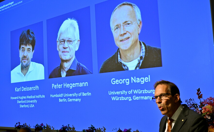 Karl Deisseroth, Peter Hegemann and Georg Nagel are shown on the screen as they are awarded the 2026 Nobel Prize in Physiology or Medicine, as announced during a press conference at the Nobel Forum at Karolinska Institutet in Stockholm, Sweden, Oct. 5, 2026.