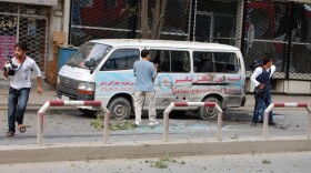 Journalists stand near a bullet-ridden van during Tuesday's attack in Kabul.