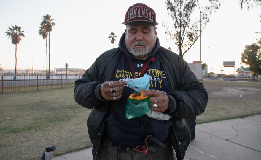 A man pulls out a mask given to him by volunteers in Calexico's Border Friendship Park, April 21, 2020.