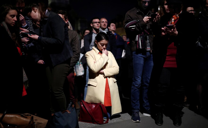 A woman prays next to Notre Dame after it sustained heavy damage from Monday's fire in Paris.