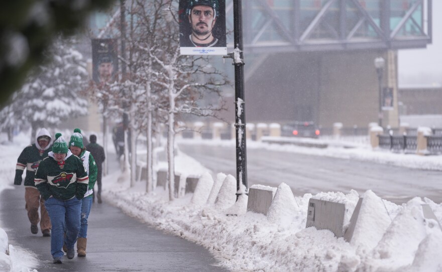 Fans walk through snowy streets before an NHL hockey game between the Minnesota Wild and Toronto Maple Leafs, Sunday, March 15, 2026, in St. Paul.