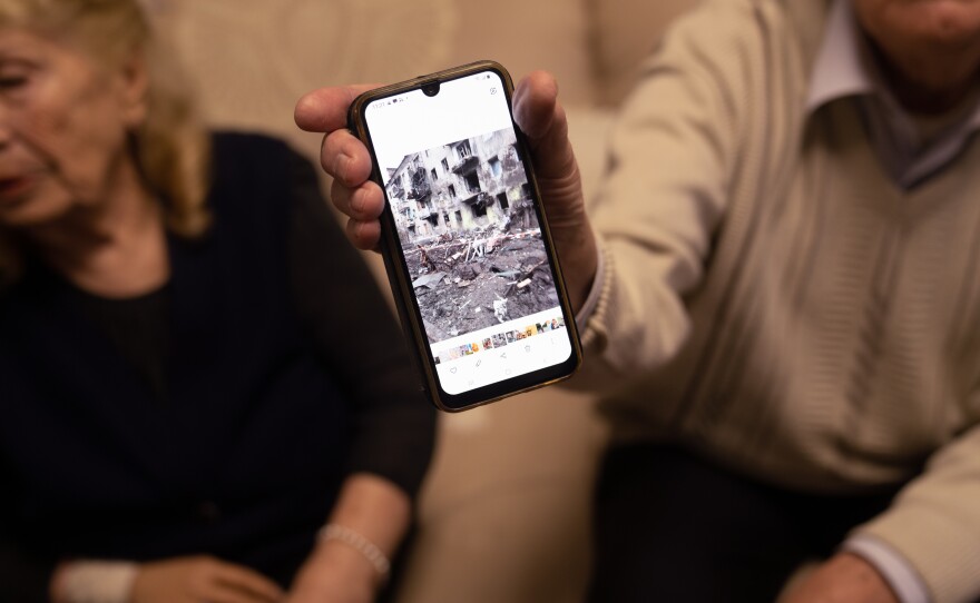 Viktor shows a photo of the damaged building where he and his wife used to live.