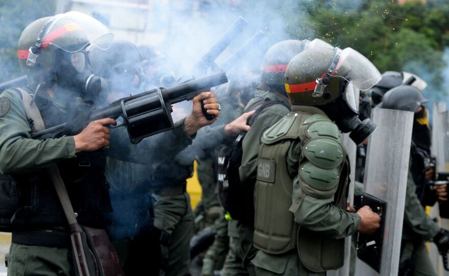 Riot police march on the protesters in the streets of Caracas on Thursday.